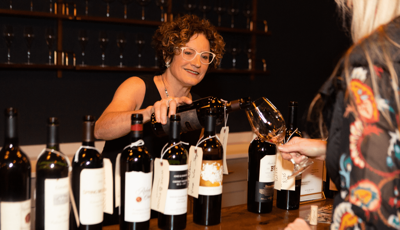 A woman pouring wine at a wine tasting event